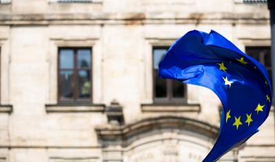 eine Flagge der Europäischen Union weht vor einem alten, repräsentativen Gebäude
