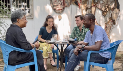 Vier MEnschen sitzen auf Plastikstühlen einander zugewandt und lachen, unterhalten sich.