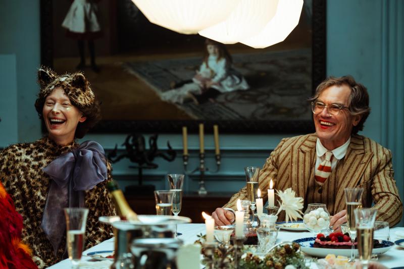 Filmszene aus "The End". Ein Mann und eine Frau sitzen verkleidet und lachend an einem reich gedeckten Tisch. c) Felix Dickinson