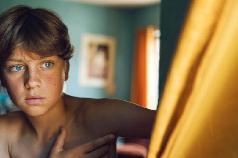 Filmszene aus: "Young Hearts". Ein junge blickt mit großen blauen Augen aus dem Bildausschnitt. c) Thomas Nolf