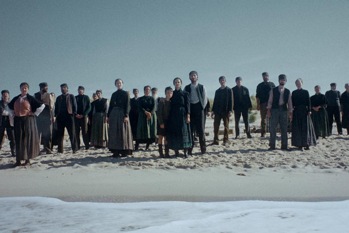 Filmszene aus "Der Heimatlose": Eine Gruppe Menschen steht am Strand