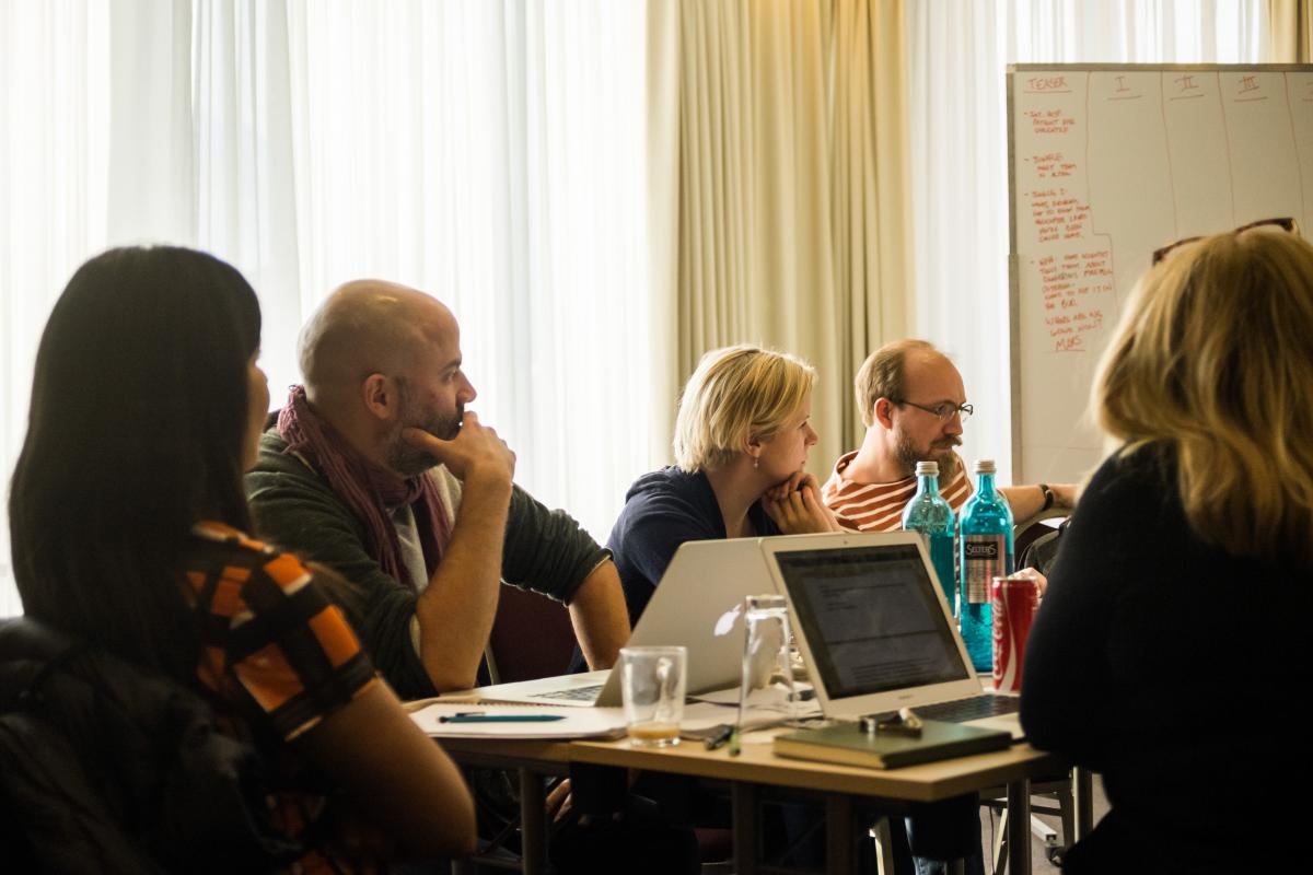Verschiedene Menschen sitzen in einem Konferenzraum und sprechen miteinander