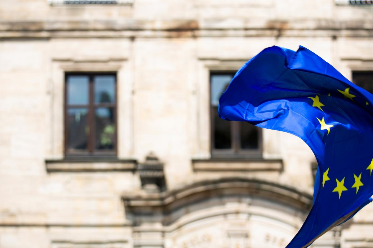 eine Flagge der Europäischen Union weht vor einem alten, repräsentativen Gebäude