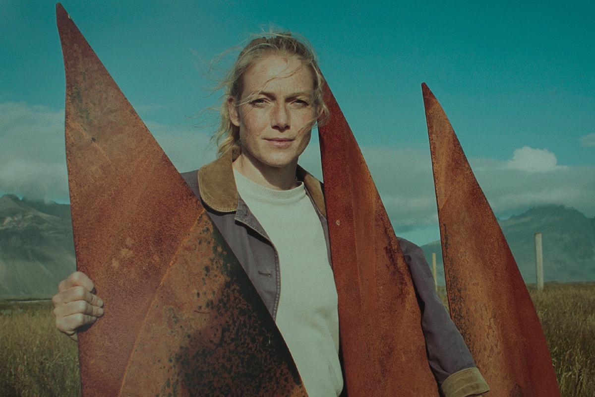 Filmszene aus The Love That Remains: Eine Frau steht vor einer Metallskulptur